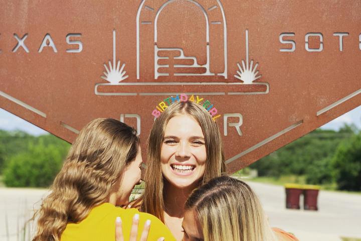 three women standing in front of a sign