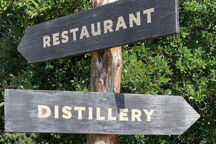 a sign pointing in the direction of a restaurant and distillery