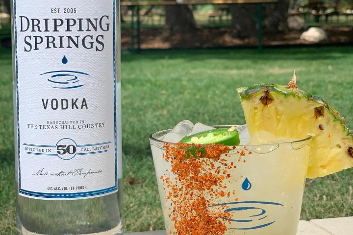 a cocktail next to a bottle of vodka